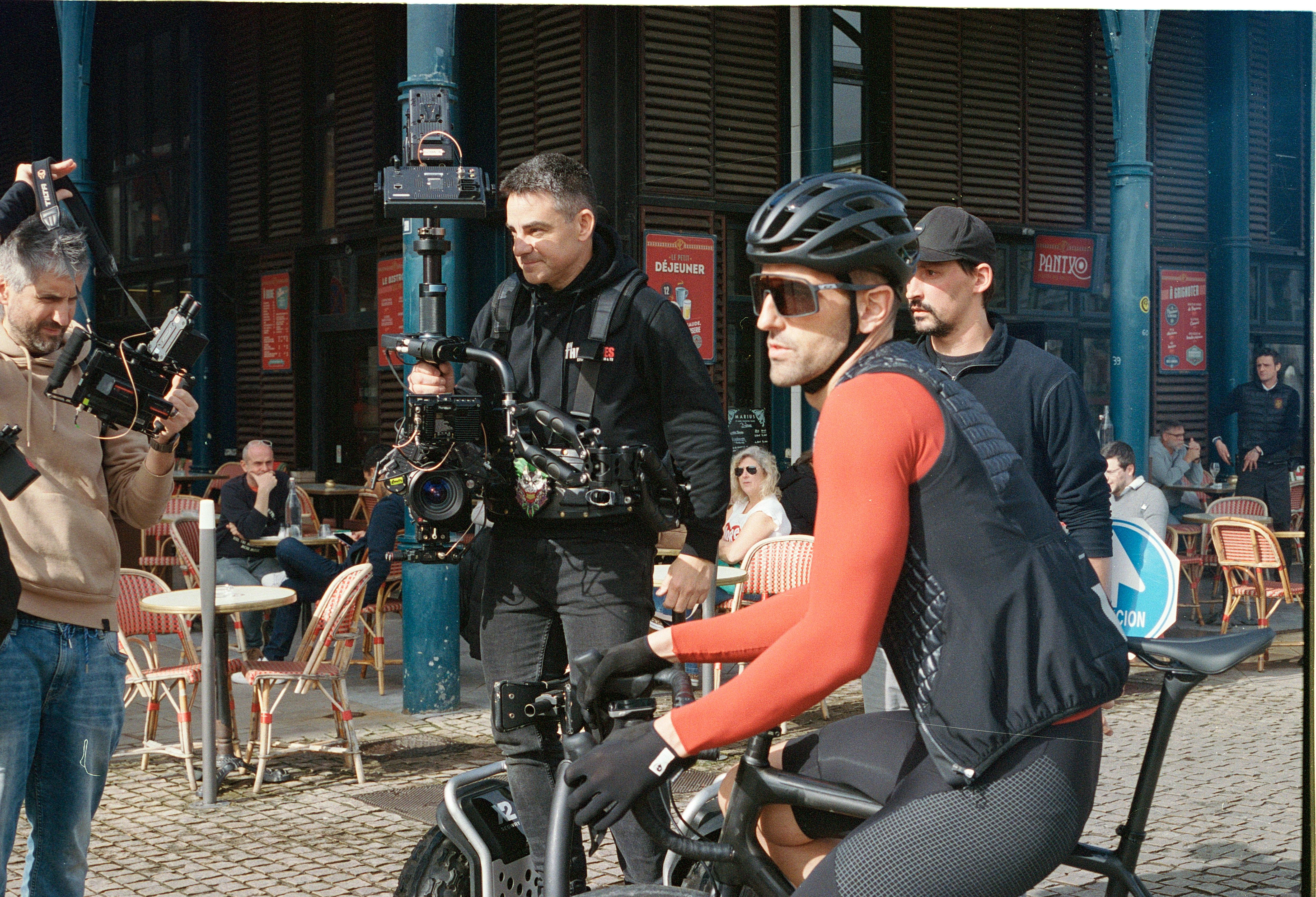 Equipo de cámara con estabilizador rodando al ciclista de la campaña Etxeondo x Eurosport frente a una terraza.